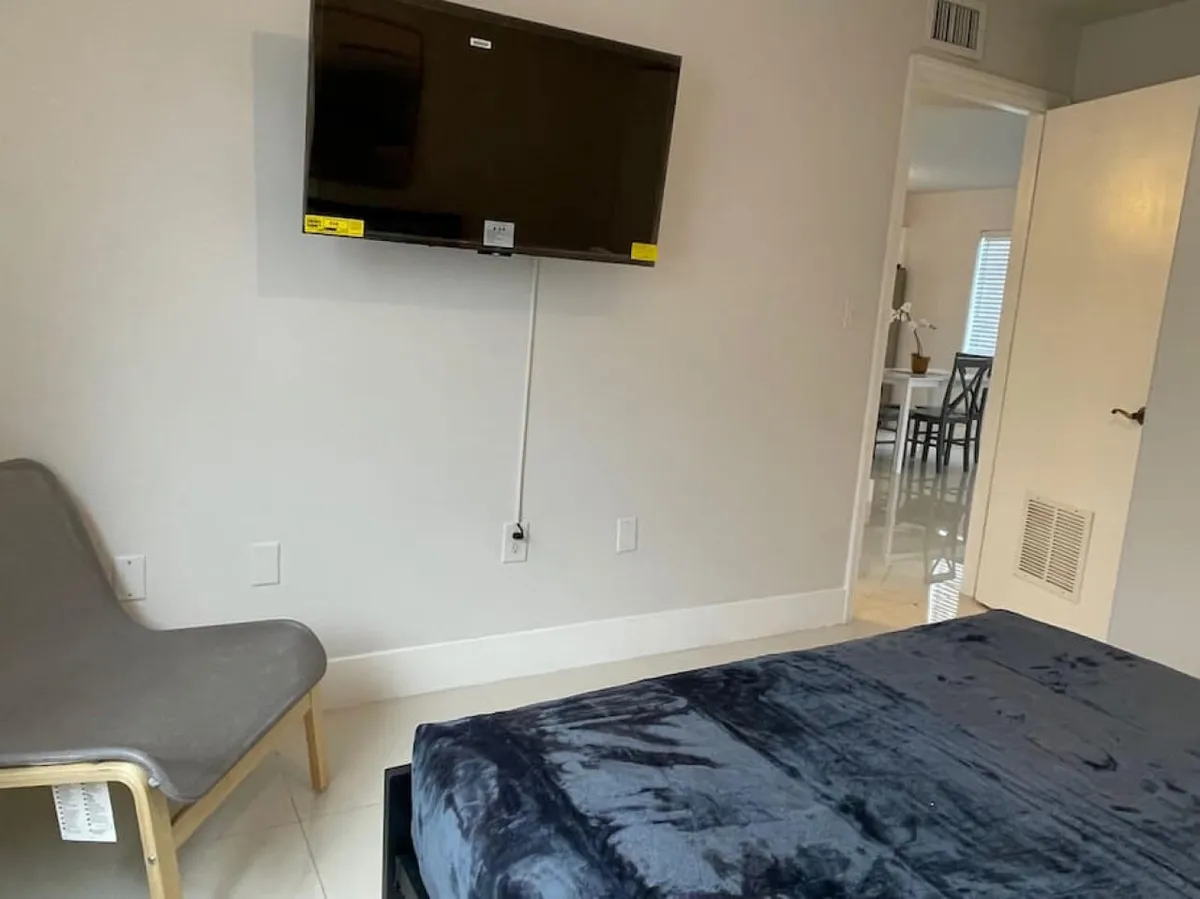 A cozy, modern interior where the dining area is partially visible close to a comfortable bed and chaise lounge. The mood is relaxed, and the setup hints at the convenience of enjoying a cup of coffee or a casual meal nearby, bridging the transition between kitchen, dining, and living spaces.